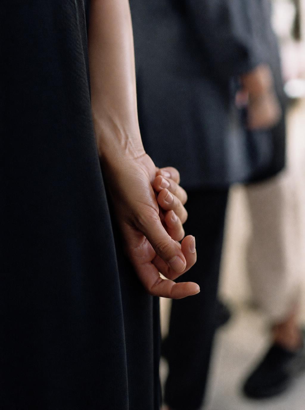 Two hands loosely interlinked during a gathering